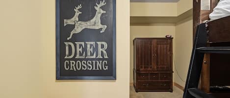 Un letrero enmarcado con siluetas de ciervos y el texto 'DEER CROSSING'.