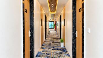 Un pasillo de hotel con alfombra estampada, puertas de madera y un diseño moderno en el techo.
