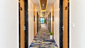 A hotel hallway with a patterned carpet, wooden doors, and a modern ceiling design. - Daksh The Royal Braj Vrindavan (Vrindavan)