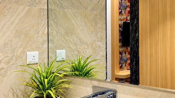 Un baño moderno con un lavabo blanco, un espejo y una planta en maceta.