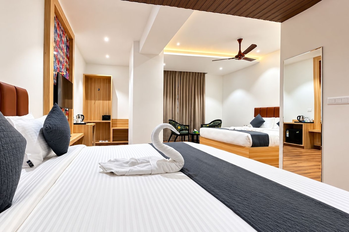 A hotel room with a large bed, a desk, a chair, a mirror, and a ceiling fan.