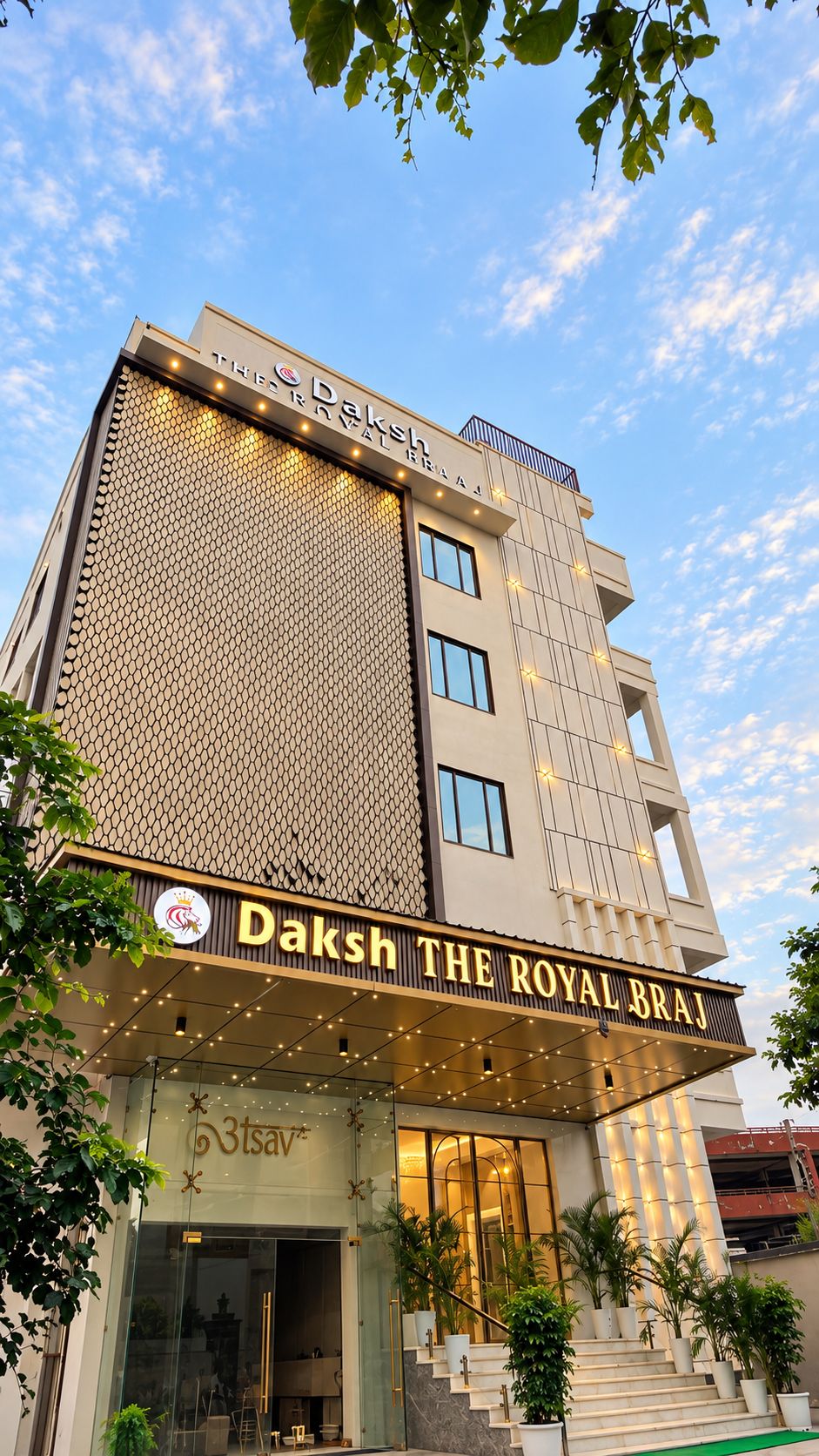Un hotel con un letrero llamativo que dice 'Daksh The Royal Braj' y una fachada moderna con un diseño de pared con motivos.