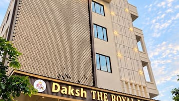 Un hotel con un letrero llamativo que dice 'Daksh The Royal Braj' y una fachada moderna con un diseño de pared con motivos.