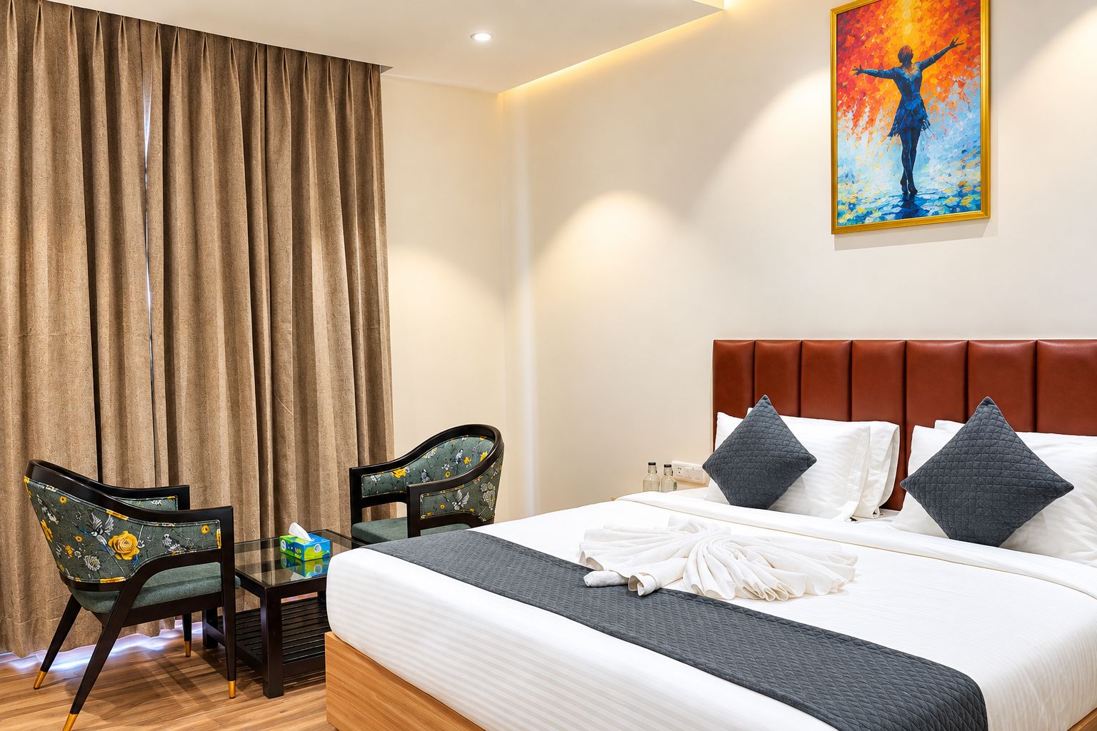 Una habitación de hotel con cama, dos sillas, un cuadro y una mesita de noche.