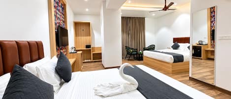 Habitación de hotel con una cama grande, un escritorio, una silla, un espejo y un ventilador de techo.