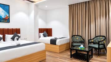 A hotel room with two beds, a ceiling fan, a painting, a window with curtains, and a small table with a chair.