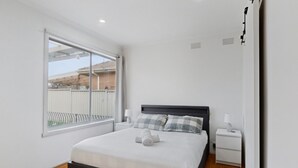 Ein Schlafzimmer mit einem Bett, Nachttischen, einem Fenster und Blick ins Freie.