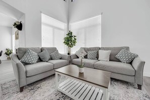 A modern living room with two grey sofas, a coffee table, and a potted plant. - 5B3B Sweet Home｜Near Strip｜Perfect for Families (Las Vegas)