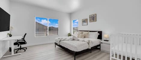 Une chambre à coucher avec un lit, un berceau, un bureau et une chaise.