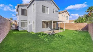 Uma casa moderna de dois andares com varanda coberta e gramado bem cuidado.