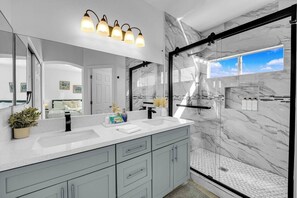 A modern bathroom with a large mirror, marble walls, a shower with a glass door, and a vanity with a sink and cabinets. - 5B3B Sweet Home｜Near Strip｜Perfect for Families (Las Vegas)