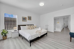 A bedroom with a bed, bedside tables, a window with blinds, a plant, and a view of a building outside. - 5B3B Sweet Home｜Near Strip｜Perfect for Families (Las Vegas)