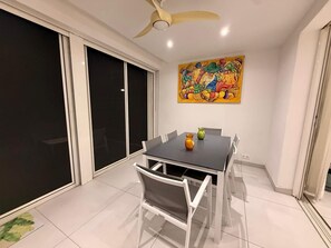 A dining area with a table and chairs, a ceiling fan, and a colorful painting on the wall. - Luxury duplex in the heart of Baie Orientale, just a few steps from the beach (SAINT MARTIN)