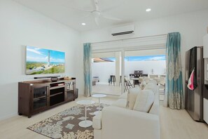 A modern living room with a flat-screen TV, a dark wooden cabinet, a white sofa, and a patterned rug. - 3BR Villa w/ Private Pool & Patio • Aruba Getaway (Noord)