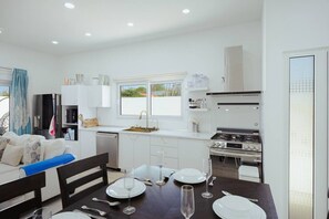 A compact kitchen with a dining area, white cabinetry, a gas stove, and a window providing natural light. - 3BR Villa w/ Private Pool & Patio • Aruba Getaway (Noord)