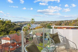 Ein Balkon mit freiem Blick auf einen Yachthafen, Wohnhäuser und eine hügelige Landschaft.