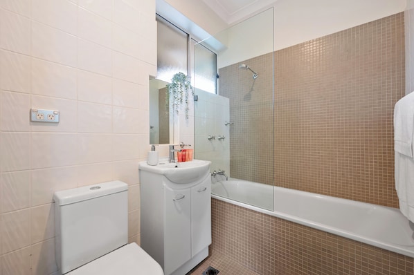 Et badeværelse med toilet, håndvask og badekar.
