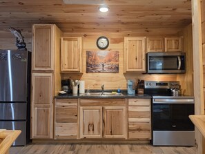 A modern kitchen with wooden cabinets, stainless steel appliances, and a clock on the wall.