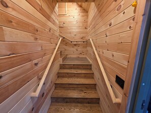A wooden staircase with a handrail, leading to an upper level.