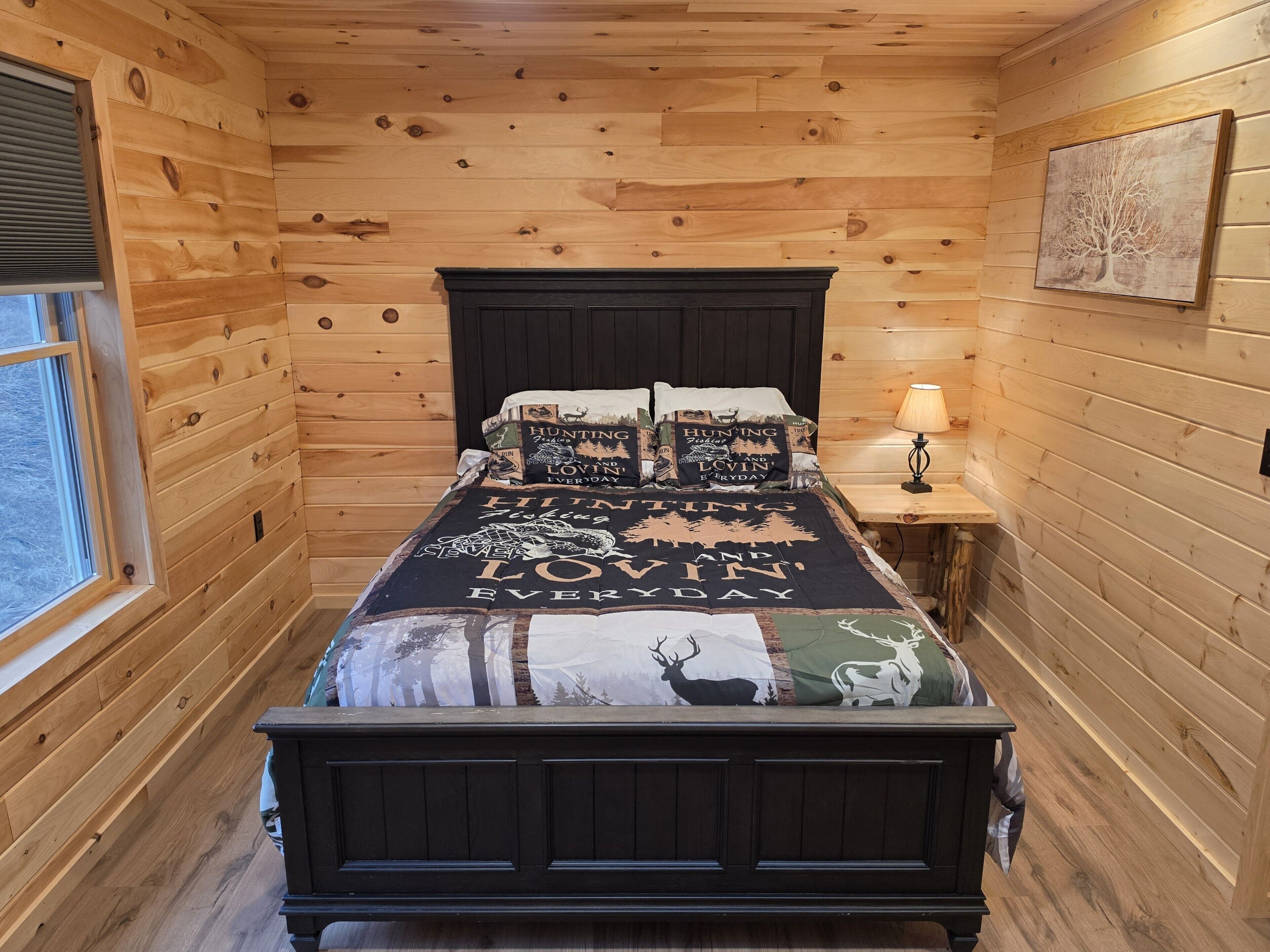 Une chambre à coucher dans un chalet en bois, avec un lit, une table de chevet, une lampe et une fenêtre.