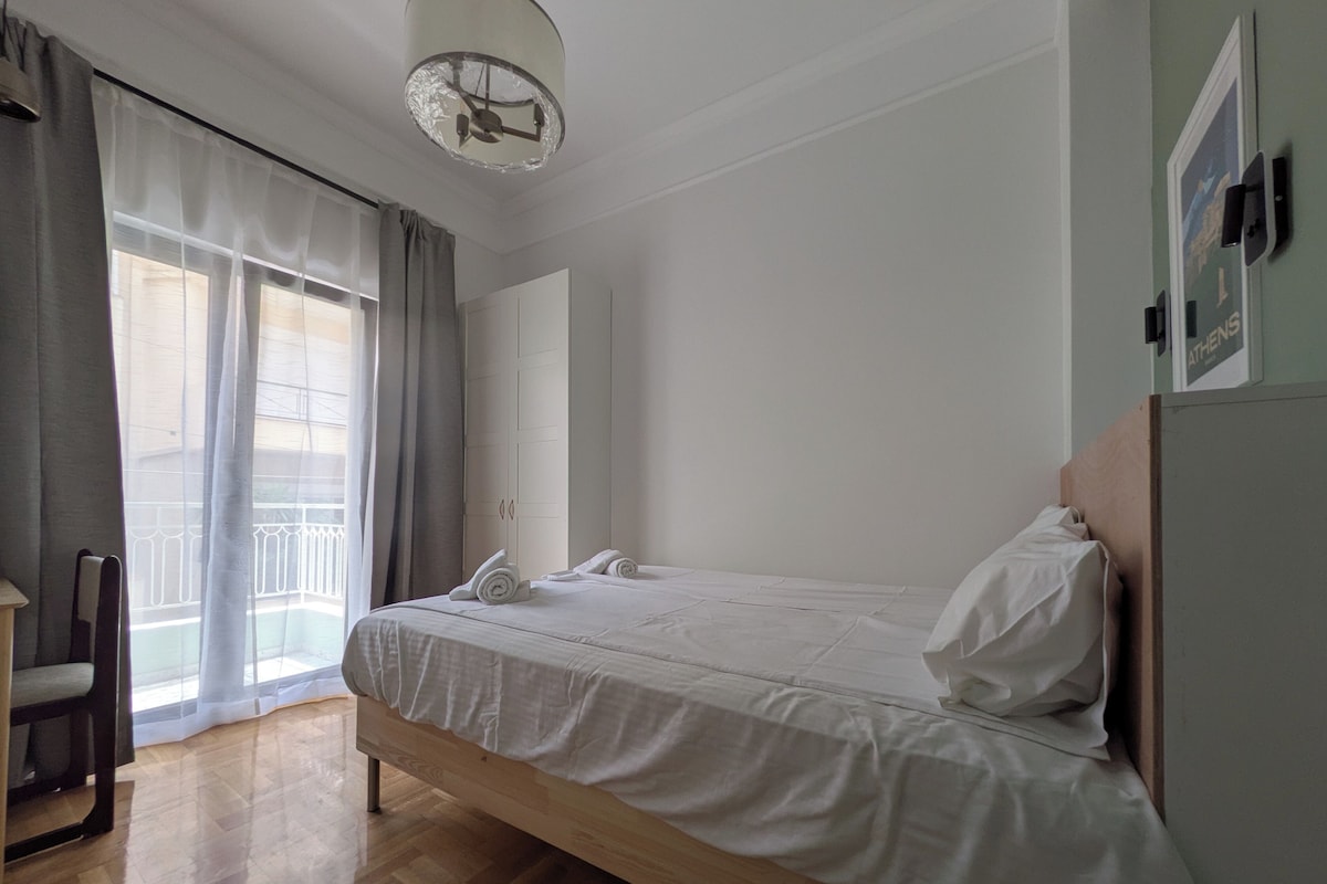 A bedroom with a wooden bed, a nightstand, a chair, and a window with curtains.