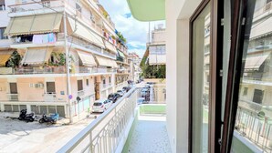 Un balcón con vistas a una calle bordeada de coches aparcados y edificios de varios pisos.