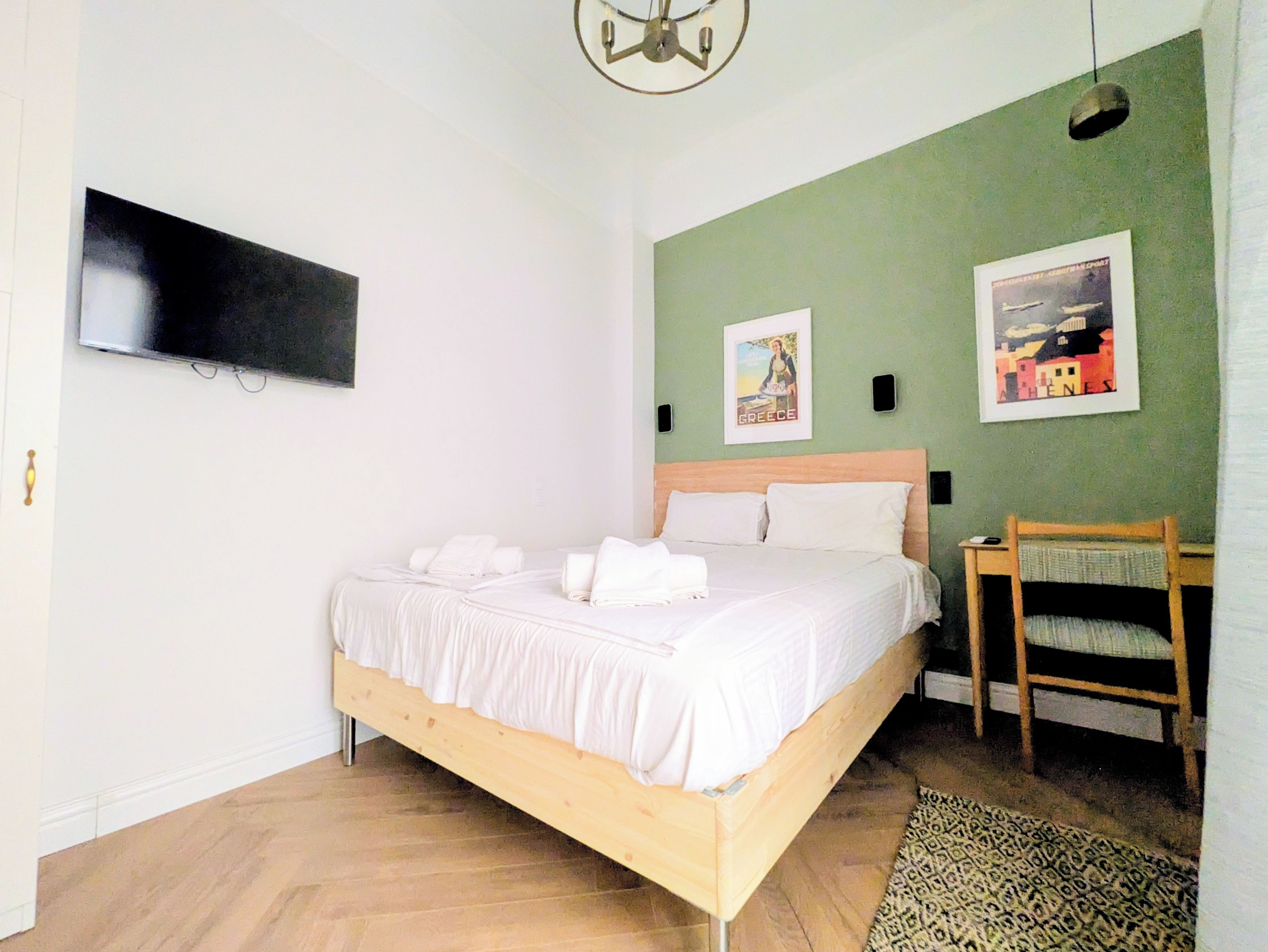 A bedroom with a bed, a chair, a television, and two wall-mounted pictures.