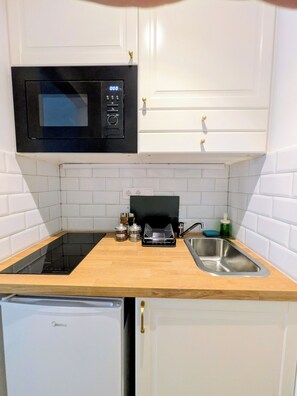 Uma cozinha compacta equipada com micro-ondas, pia e lava-louças.