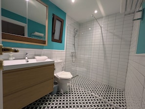 A bathroom with a white sink, a wooden vanity, a white toilet, and a shower area with white tiled walls and floor. - d52 - Dinostratus House (Athina)