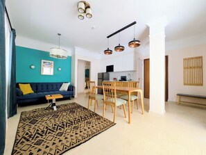 A modern living room with a sofa, a dining table, and a kitchen in the background. - Dinostratus House - Boutique Rooms and Apartments near Acropolis and Metro (Athina)