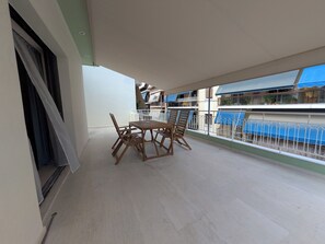 A balcony with a table and chairs, a view of neighboring buildings, and a railing. - d52 - Dinostratus House (Athina)
