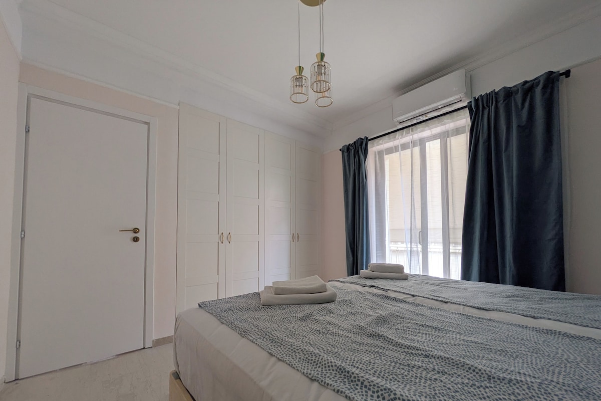 A bedroom with a bed, wardrobe, and a window with curtains.