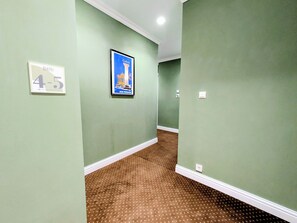 A hallway with green walls, a brown patterned carpet, and a framed poster of a building. - Dinostratus House - Boutique Rooms and Apartments near Acropolis and Metro (Athina)