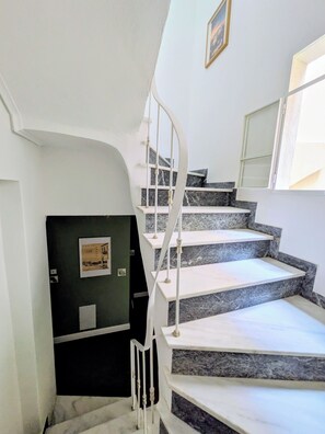 Eine Treppe mit weißen Geländern und Marmorstufen, die zu einer Zwischenebene führt.