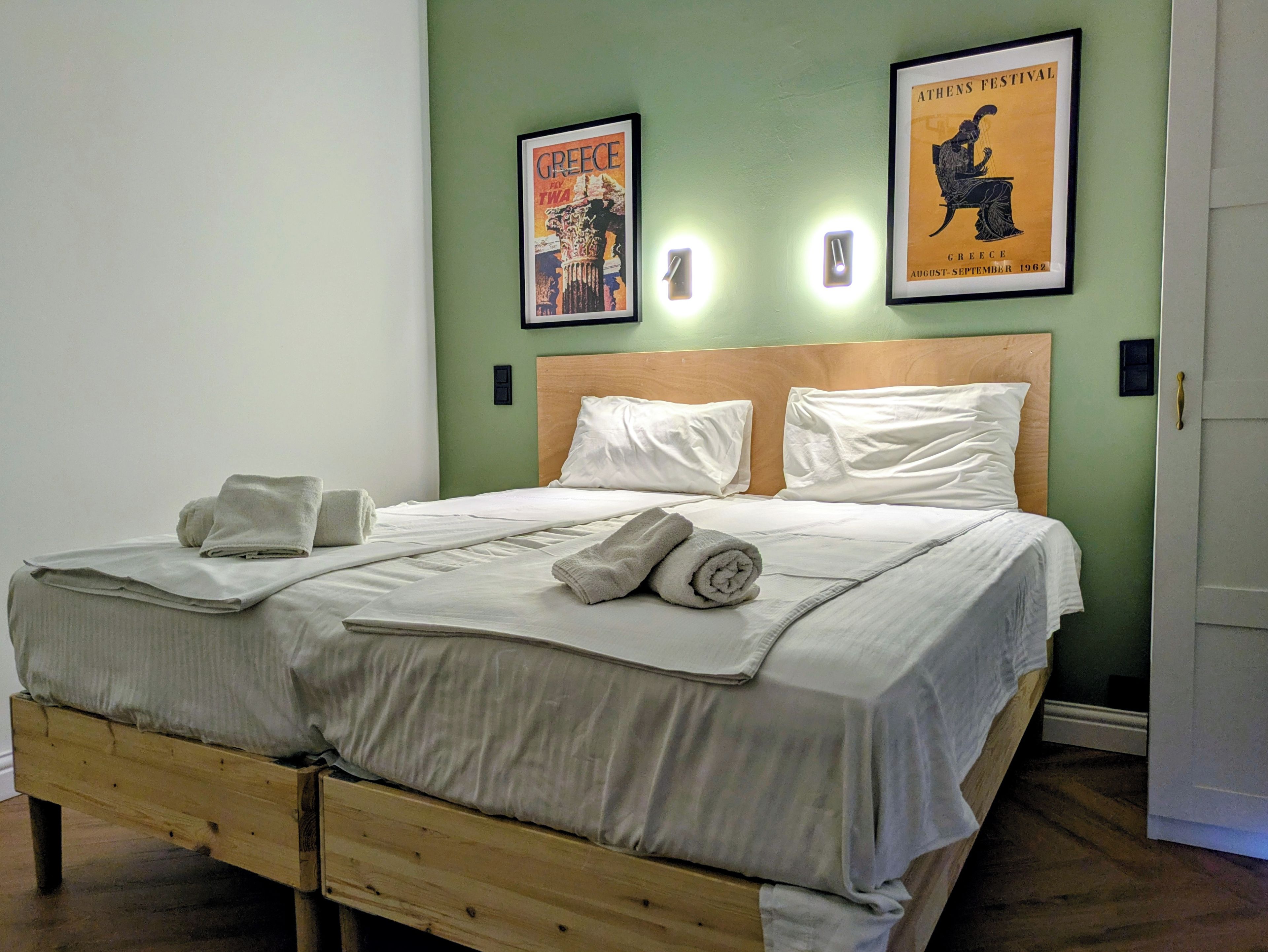 Ein ordentlich bezogenes Bett mit weißen Leinen und Handtüchern, ein hölzerner Kopfseitenverkleidung und zwei gerahmte Poster an der Wand.