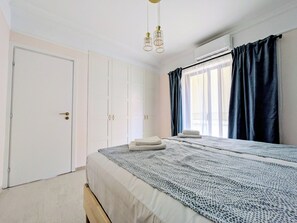A bedroom with a bed, a wardrobe, a window with curtains, and a ceiling light fixture. - Dinostratus House - Boutique Rooms and Apartments near Acropolis and Metro (Athina)
