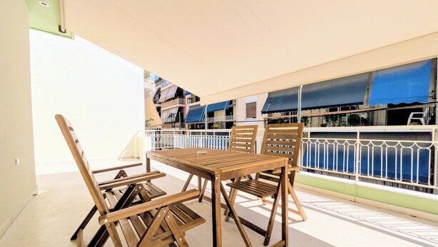 Un conjunto de mesa y sillas de madera en un balcón con vista a edificios.