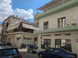 A multi-story building with balconies, a gated entrance, and parked cars. - d52 - Dinostratus House (Athina)