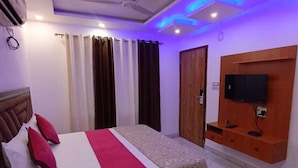 Quarto de hotel com cama, cortinas, televisão e ventoinha no teto.