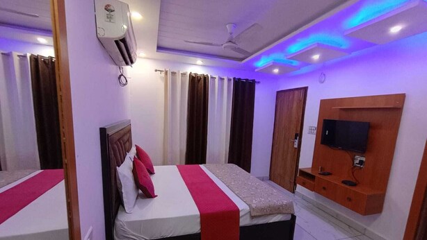 Quarto de hotel com cama, televisão, escrivaninha e cadeira.