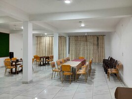 Un salón de conferencias con una mesa larga, varias sillas y una pantalla para proyector.