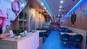 Interior de restaurante com balcão, área de estar e ventiladores de teto.