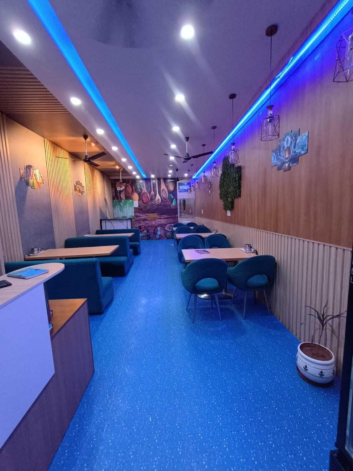 Un restaurante con cabinas y mesas, moqueta azul y detalles de iluminación azul.