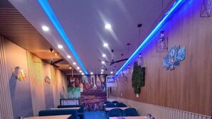 Um restaurante com cabines e mesas, carpete azul e detalhes de iluminação azul.