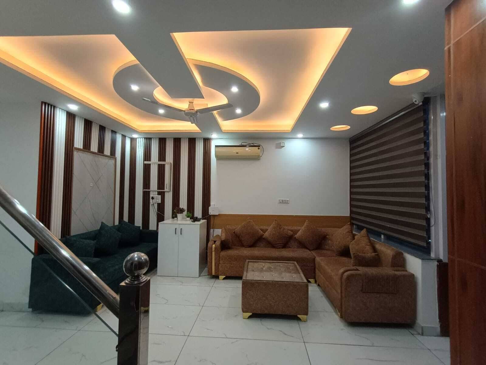 Una sala de estar moderna con un sofá, una mesa de centro, una escalera e iluminación empotrada en el techo.
