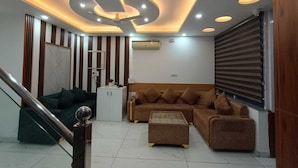 Uma sala de estar moderna com sofá, mesa de centro, escada e teto com iluminação embutida.