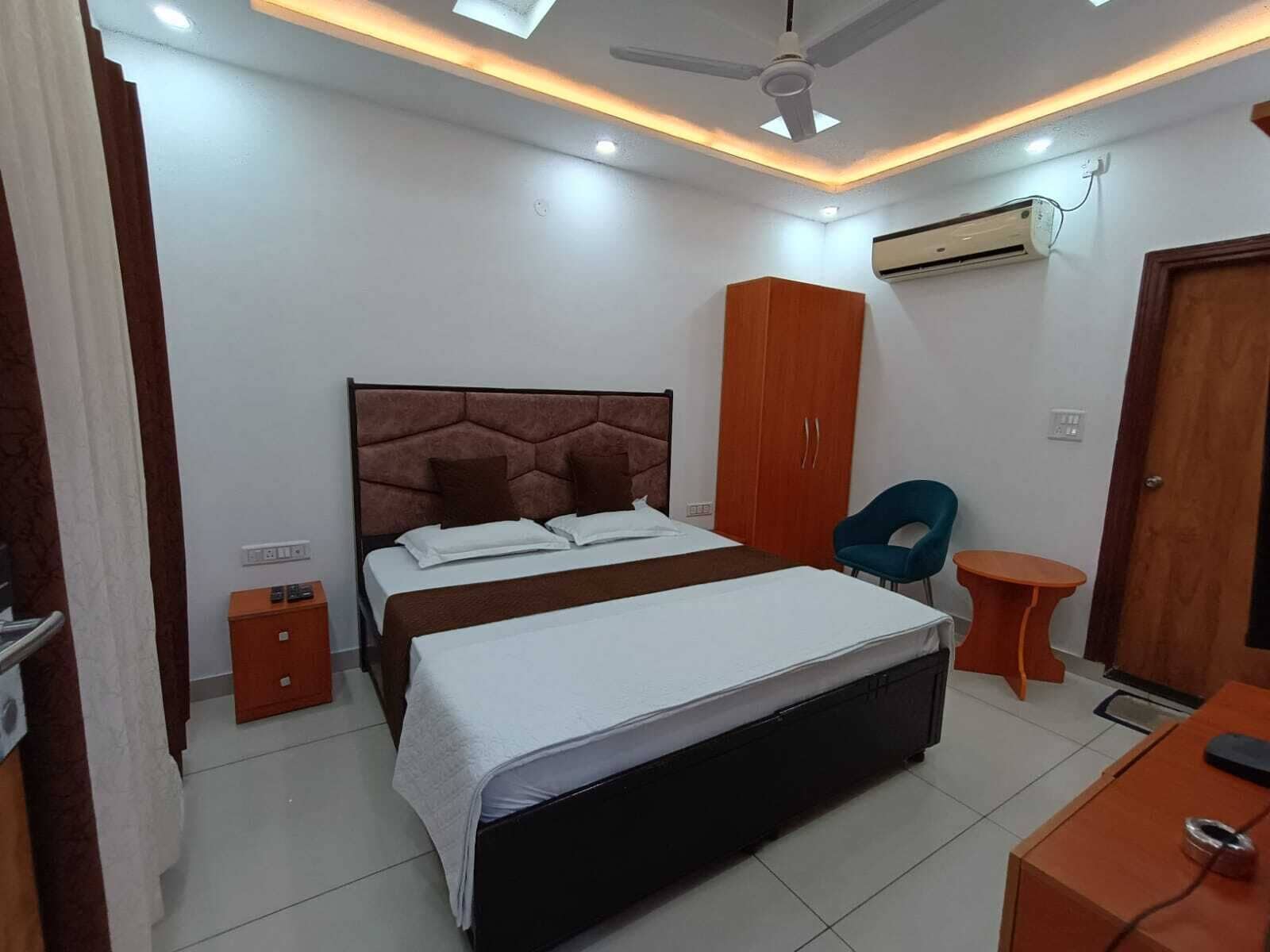 Un dormitorio con cama, armario, silla y una pequeña mesa.