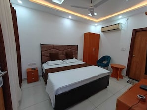 Un dormitorio con cama, armario, silla y una pequeña mesa.