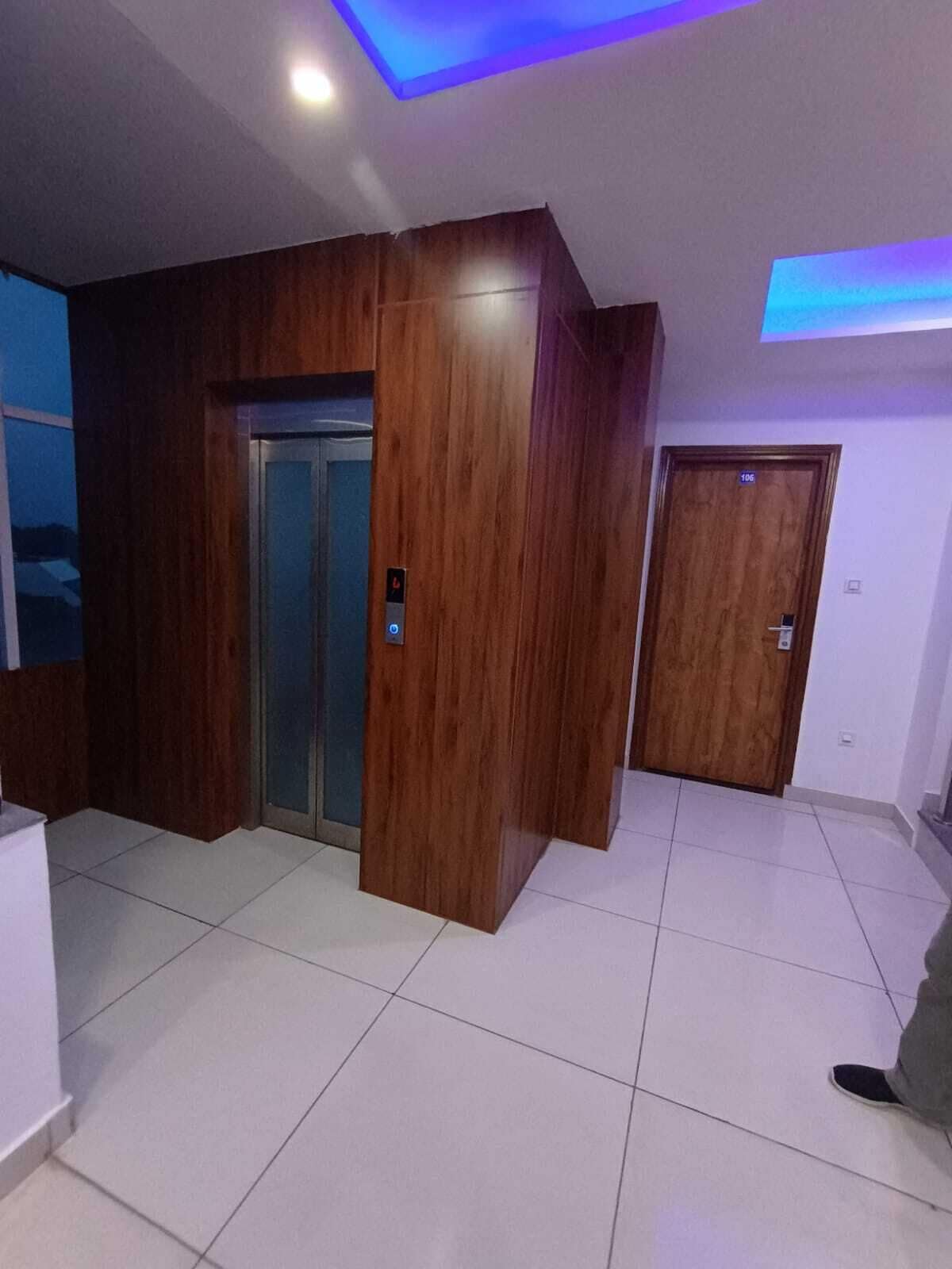 Una habitación con pared de paneles de madera, piso de baldosas y una puerta con el símbolo del número.