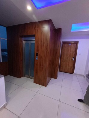 Una habitación con pared de paneles de madera, piso de baldosas y una puerta con el símbolo del número.